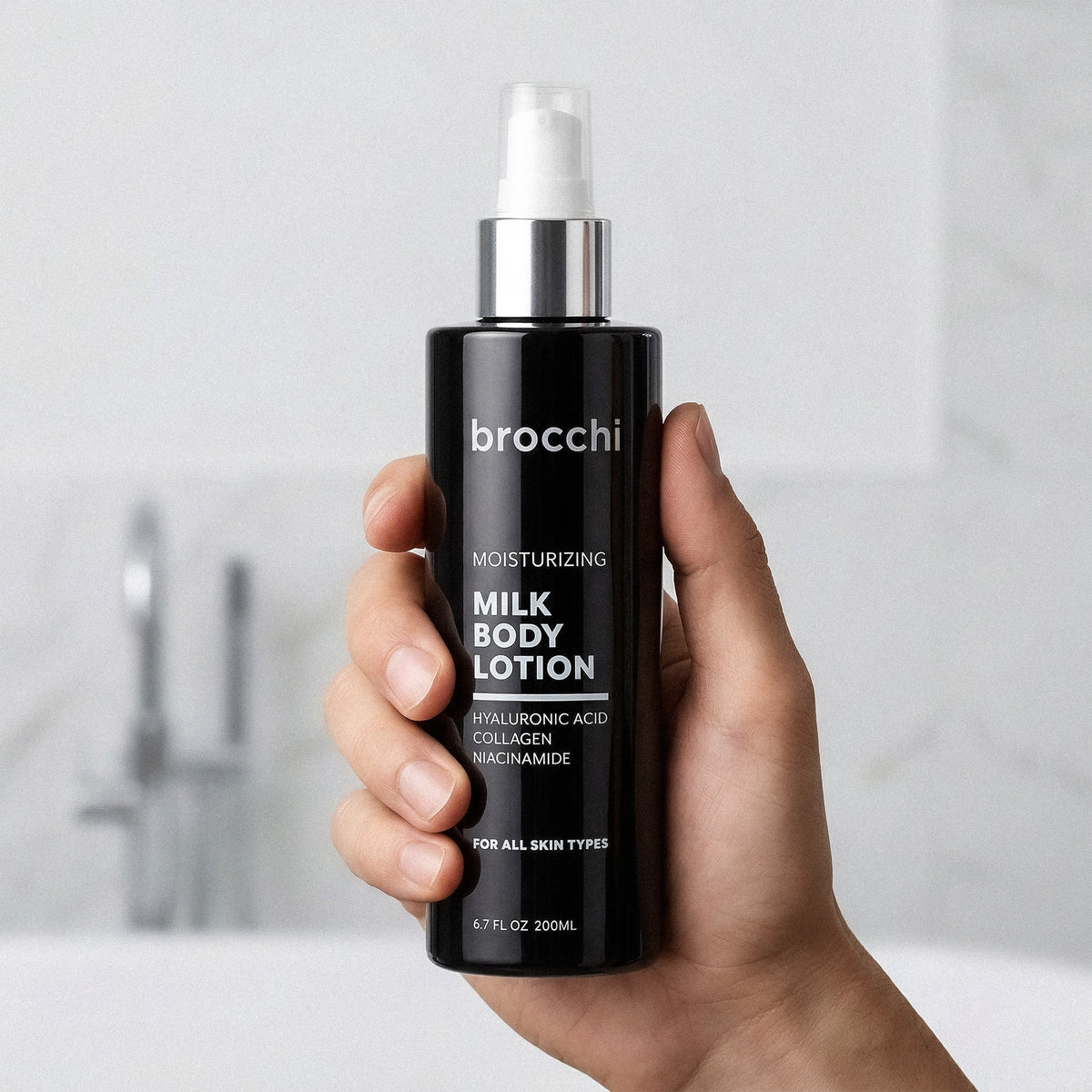 Milk Body Lotion bottle held in hand in a bathroom